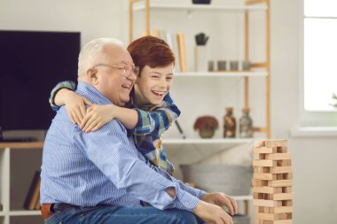 Mutlu küçük torun birlikte oyun oynarken büyükbabasını kucaklıyor.