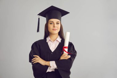 Geleneksel bonet ve manto mezunu kadın üniversite mezunu elinde diplomayla ayakta duruyor