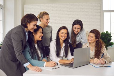 Mutlu iş kadınları ofiste buluşup online mağazaları için fikirleri tartışıyor.