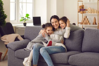 Mutlu anne kızlarına sarılıyor, onlar da bayram için ona bir tebrik kartı veriyor..