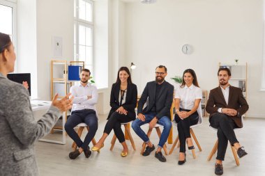 Kadın yönetmen, çalışanlarına ofiste yeni iş fikirleri hakkında jest yapar ve konuşur..