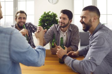 Dört gülümseyen adam masada bira içip silah yarışı yapıyorlar.