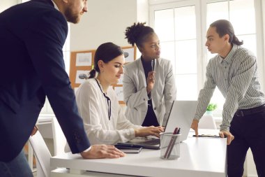 Genç meslektaşlar bir dizüstü bilgisayara veri yazarak bir girişim fikrini veya yeni bir iş projesini tartışıyor.