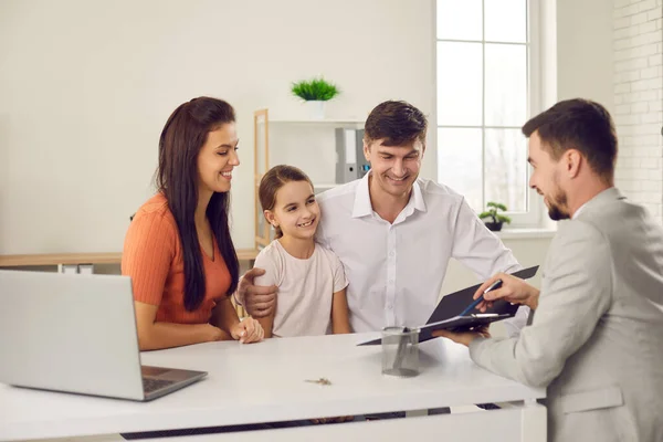 Happy family with daughter sitting and looking at contract points in hands of real estate agent