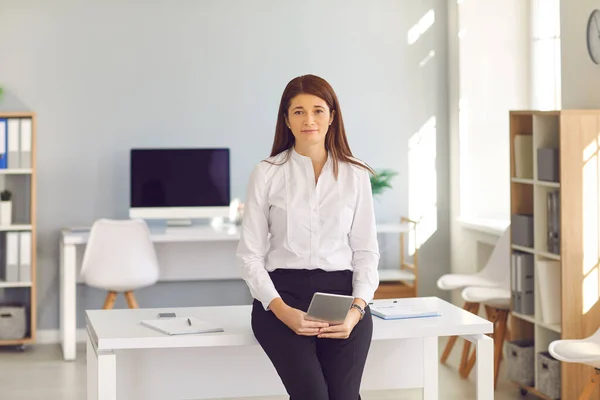 Portrait of executive professional businesswoman standing with digital tablet in hands.