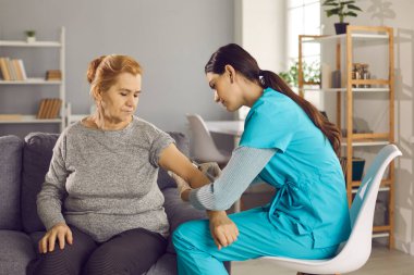 Yetişkin ve yaşlı bir kadının eline ilacı enjekte eden uzman hemşire..