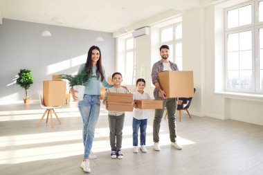 Yeni eve taşınırken karton kutular taşıyan mutlu ebeveynler ve çocuklar.