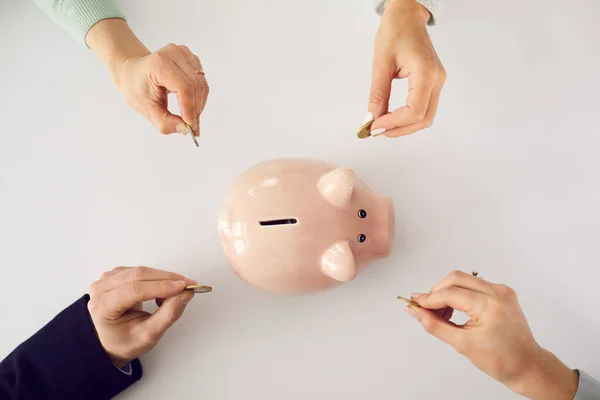 From above shot of peoples hands putting money in pink piggy bank on white background — Stock Photo, Image