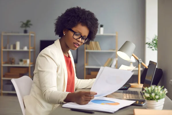 Empresaria afroamericana trabajando con documentos y laptop en escritorio de oficina — Foto de Stock