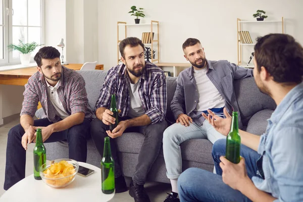 Male friends are drinking beer and having a pleasant conversation, spending a time together.