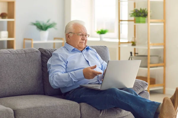 Senior man staying in touch with relatives video calling them on laptop computer