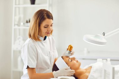 Genç ve güzel bir kadın ultrasonik cilt tazeleme prosedüründen zevk alıyor.