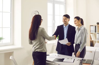 Banka müdürü, borsacı ya da emlakçı mutlu genç çiftle el sıkışıyor.