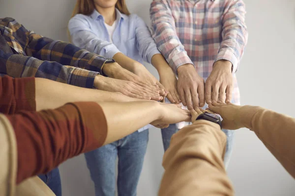 Group of young people join hands showing team spirit and determination to achieve success