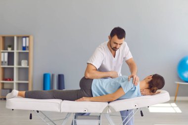 Kendine güvenen erkek doktor kayropraktik uzmanı ya da osteopat kadın ve bacak eklemlerini düzeltiyor.