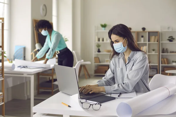 Multiethnic woman coworker in face mask working in office keep distance