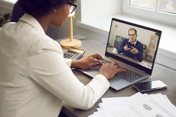Employee having online work meeting with her boss via video call on laptop computer
