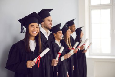 Üniversite mezuniyet sınıfının yan görünüşü. Diplomalar duvarın yanında duruyor..