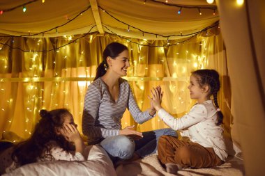 Mutlu anne akşam çadırında iki sevimli kızla oynuyor.