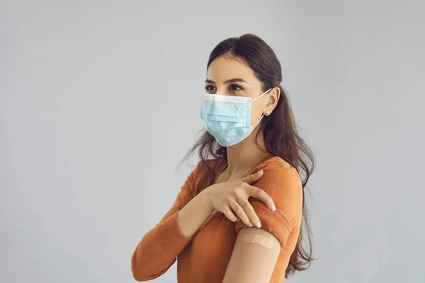 Donna felice indossando maschera viso medico mostra il braccio dopo aver ricevuto Covid 19 vaccino — Foto Stock