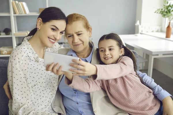 Happy family moments. Little girl taking a selfie with her mother and grandmother.