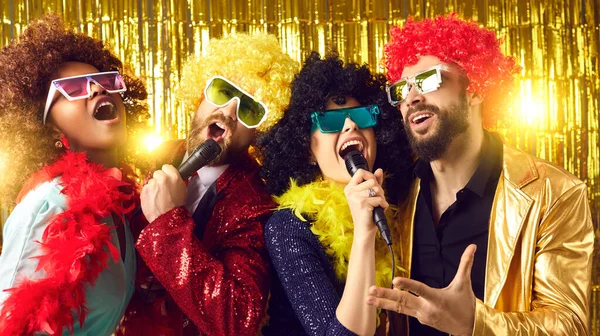 Grupa szczęśliwych ludzi w śmieszne peruki i kostiumy śpiew i zabawy na karaoke party — Zdjęcie stockowe