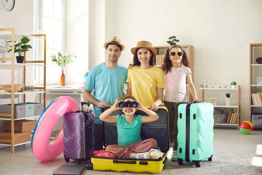 Portrait of happy young family with suitcases ready to go on summer holiday trip