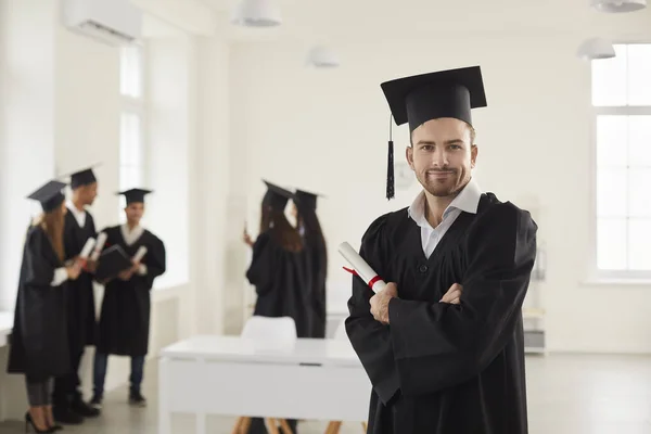 Портрет студента в уніформі випускника університету і з дипломом в руці . — стокове фото