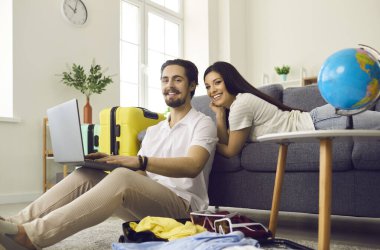 Tatil gezisi planlayan genç bir çift ve dizüstü bilgisayarla bilet ya da otel odası alıyorlar.