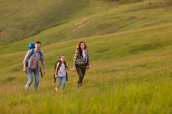 Šťastná rodina s batohy cestovat přes kopce na venkově v létě. — Stock fotografie