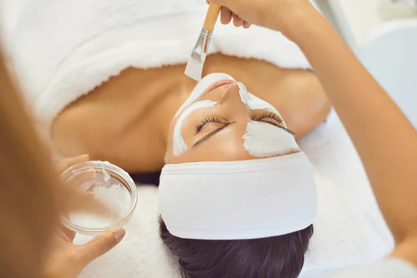 Jovem relaxada deitada na mesa de spa e desfrutando de procedimentos de beleza de cuidados faciais — Fotografia de Stock