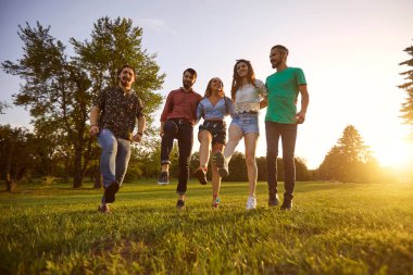 Kaygısız arkadaşlar yaz parkında sarılıyorlar.