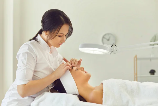 Vrouw dermatoloog aanraken van vrouwen voorhoofd tijdens het huidonderzoek — Stockfoto