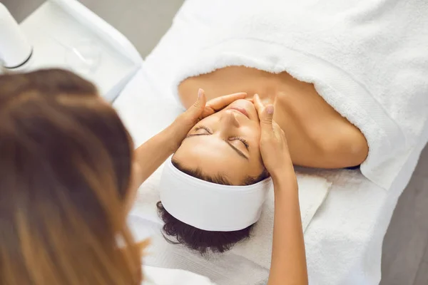 Jonge mooie vrouw heeft ontspannen en geniet van een gezichtsmassage van een spa specialist. — Stockfoto