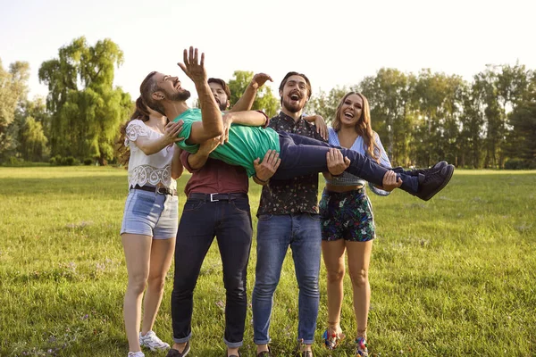 Vrolijke jonge vrienden die zich vermaken op het platteland op zomerdag. Groep mensen die lachen en dom doen in de natuur — Stockfoto