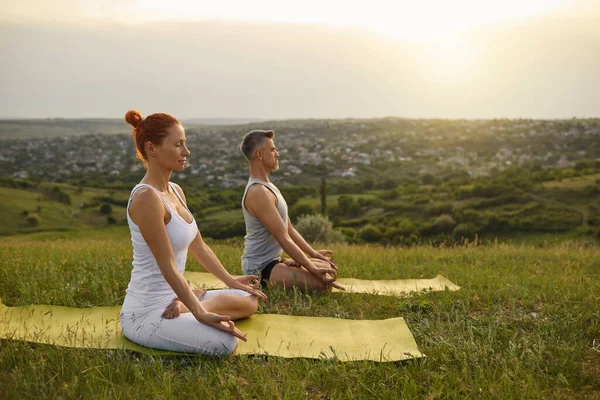 Mann und Frau meditieren bei Sonnenuntergang auf dem Land — Stockfoto