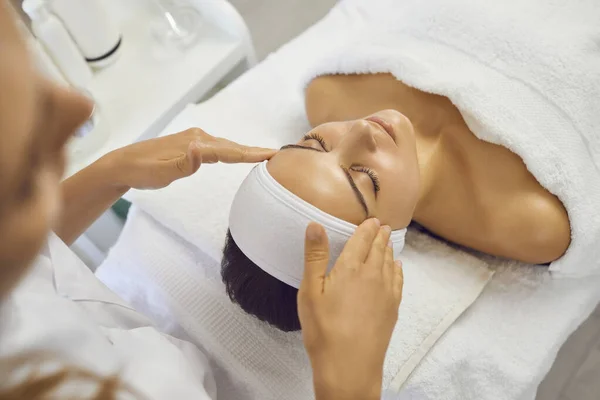 Kvalificerad massör gör ansiktslyftning för kvinna, som kom på resort center för anti-agin massage. — Stockfoto