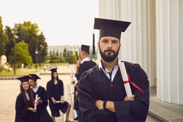 Portrét sebevědomého a radostného studenta v podobě absolventa s diplomem v ruce. — Stock fotografie