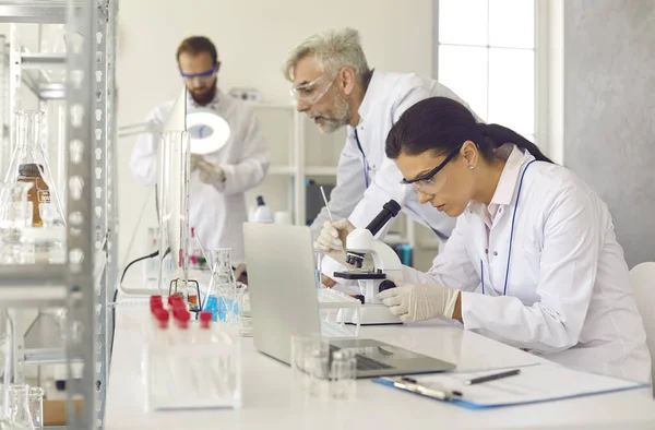 Laboratoriumwetenschappers werken met laboratoriumapparatuur op moderne werkplek — Stockfoto