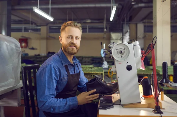 Portrait of a skilled shoe factory worker who makes mens leather shoes at his workplace.