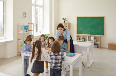 Friendly caucasian female teacher having fun to teach a lesson to children in elementary school.