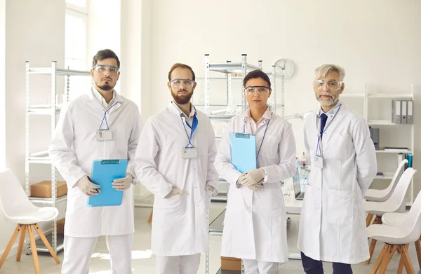 Retrato de membros do grupo de pesquisa médica em jalecos e óculos em pé em laboratório — Fotografia de Stock