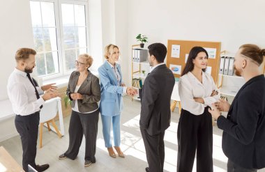 Group of diverse confident business people men and women in formal clothes talking after meeting. Company employees chatting in modern office during job conference discussing work project.