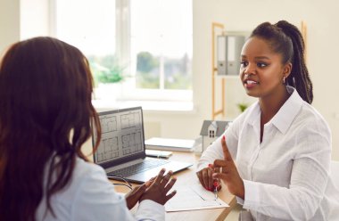 Genç Afro-Amerikan kadınları dizüstü bilgisayar, tasarımcı ya da mimar ofis danışmanlığıyla konuşuyor. Ev planına göz atan, maliyetleri tartışan, emlak hizmetlerinde daire alıp satan kadın çalışanlar.