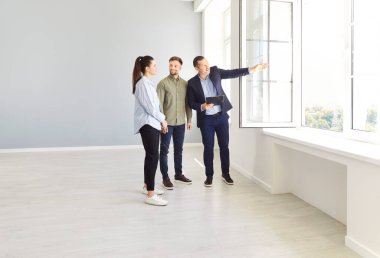 Realtor or real estate agent conducts a presentation of a new house or apartment, preparing the couple for purchase or rent. The property is showcased as part of a professional real estate service.