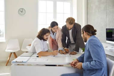Colleagues in the office work together on a business project comparing data and analyzing lists on paper. Business partners work in the bright office of the business center. Concept of teamwork.
