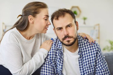 Woman whispering to mans ear reflects influence, manipulation, or persuasion concept. Emotional control, relationship dynamics, and hidden intentions. A visual metaphor of power and secrecy.