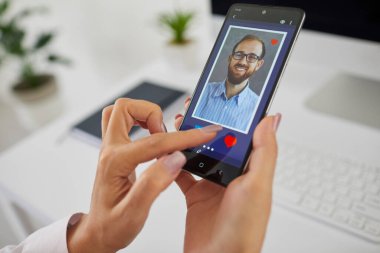 Kadın parmağı, cep telefonu ekranında randevu uygulaması ya da site kullanmak gibi. Bekar genç bir kadın, aşkı, partneri ve sevgilisini bulmak için akıllı telefondaki ilişki profilini çalıyor.