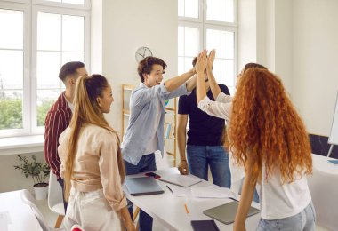 Students in class, two teens girl and guy are giving five each other another classmates looking at them standing near. Carefree student life. Education, studying in highschool, college, university.