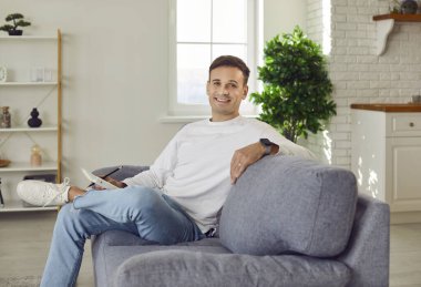 Mutlu bir adamın portresi, evdeki bir kanepede oturup, hak ettiği serinliği alıyor. Özgün gülümseme, bu dinlenme anında dinlenirken rahatlama ve mutluluk yayar..